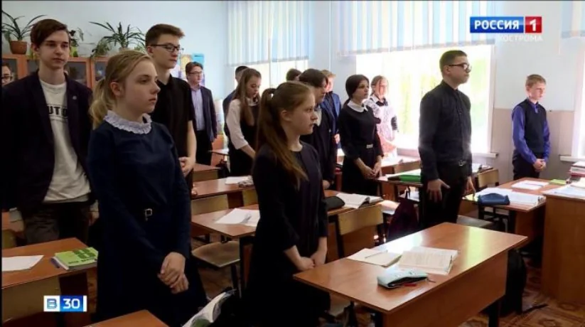 Школьники стоят у парт во время минуты молчания